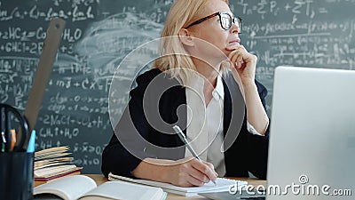 Un insegnante adulto serio che lavora in classe scrivendo alla scrivania prendendo appunti stock footage Un insegnante adulto serio che lavora in classe scrivendo alla scrivania prendendo appunti stock footage