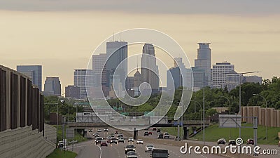 Un lavaggio della luce arancio di pomeriggio sopra l'orizzonte distante di Minneapolis e del traffico stradale nella priorità alt video d archivio Un lavaggio della luce arancio di pomeriggio sopra l'orizzonte distante di Minneapolis e del traffico stradale nella priorità alt video d archivio