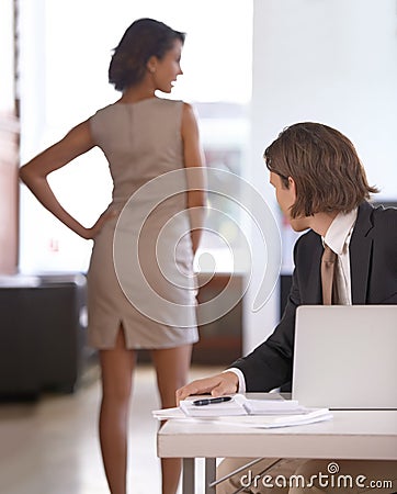 Unable to resist the temptation. Young man checking out a coworkers behind at work. Stock Photo