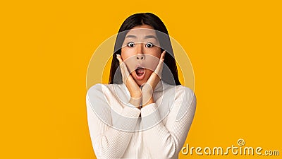 Unbelievable! Shocked girl with open mouth and hands on cheeks Stock Photo