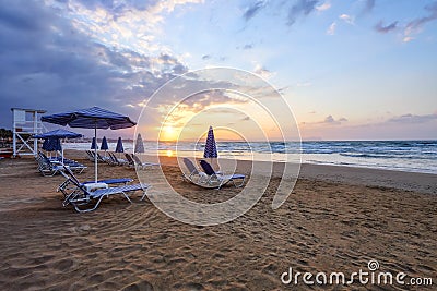 Unbelievable sunrise. Empty beach with umbrellas and deck chairs closed. Beautiful summertime view seascape. Morning landscape. Stock Photo