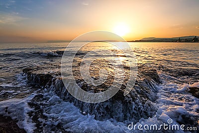 Unbelievable sunrise is reflecting on the water. Morning landscape with mountains. Beautiful sea with waves. Romantic relax place. Stock Photo
