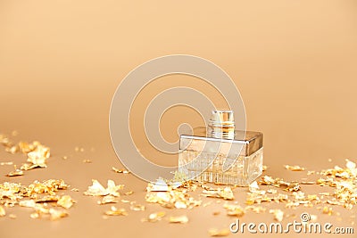 Unbranded perfume spray bottle and pieces firecracker gold paper on golden background. Mockup with copy space. Bottle for branding Stock Photo