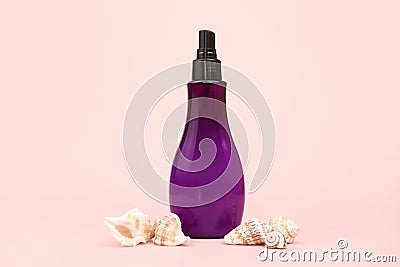 Unbranded purple plastic spray bottle and many different sea shells on pink background. Cosmetic packaging mockup with copy space Stock Photo