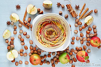 Uncooked apple tart in the baking dish decorated with fresh sliced apples, hazelnuts, cinnamon sticks, anise stars. Homemade pie Stock Photo