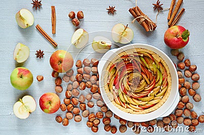 Uncooked apple tarte tatin in the baking dish decorated with fresh sliced apples, hazelnuts, cinnamon sticks, anise stars Stock Photo