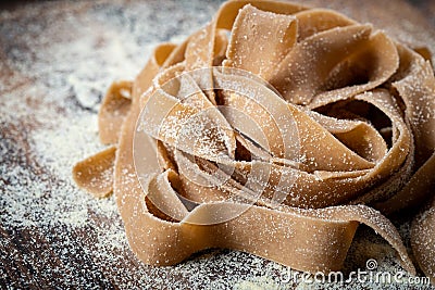 Uncooked brown pasta tagliatelle with chestnuts on a wooden Stock Photo