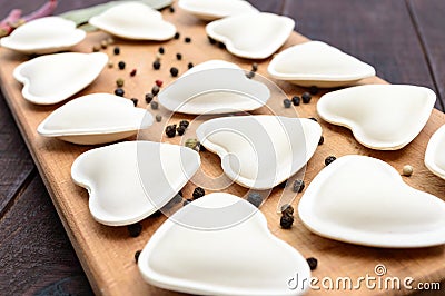 Uncooked dough in the shape of a heart dumplings, ravioli, pelmeni, on a cutting board Stock Photo