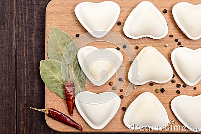 Uncooked dough in the shape of a heart dumplings, ravioli, pelmeni, on a cutting board. Stock Photo