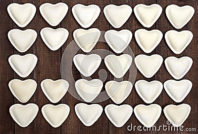 Uncooked dough in the shape of a heart dumplings, ravioli, pelmeni, laid out in rows Stock Photo