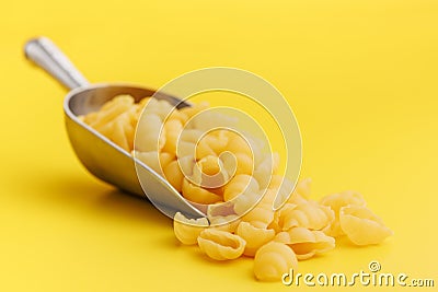 Uncooked gnocchi pasta. Raw italian pasta in scoop on yellow background Stock Photo