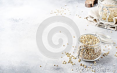 Uncooked green buckwheat groat in glass jar, healthy vegetarian food on gray kitchen table, copy space, selective focus Stock Photo