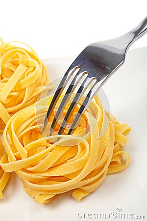 Uncooked pasta nests and fork Stock Photo