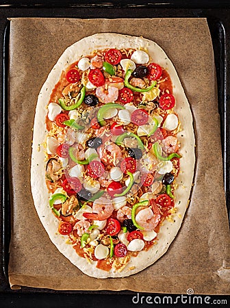 Uncooked pizza prepared for baking on a sheet for baking. Italian food. Top view Stock Photo