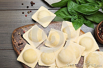 Uncooked ravioli, basil and peppercorns on wooden table, closeup Stock Photo