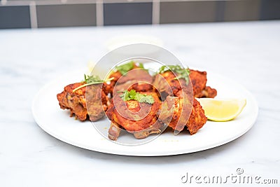 uncooked tandoori chicken thighs on a white plate Stock Photo