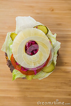 Uncovered burger with pineapple and tomato on the table Stock Photo