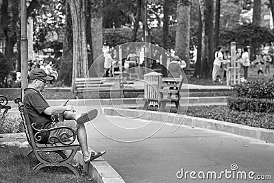 Ho Chi Minh City, Vietnam - September 1, 2018: an undefined old man is resting and listening to music in the park in the morning. Editorial Stock Photo