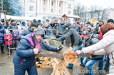 Undefined people take part in contest saw up the log during Maslenitsa celebration in Bryansk city. Editorial Stock Photo
