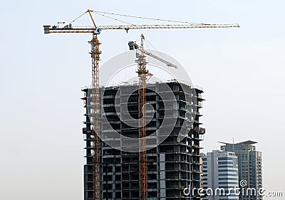 Under construction tall building skyscraper with yellow construction cranes next to it Stock Photo