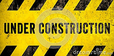 Under construction warning sign text with yellow black stripes painted over concrete wall cement facade texture background banner Stock Photo