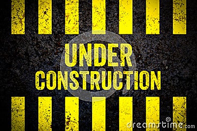 Under construction warning sign with yellow and black stripes painted over cracked concrete wall weathered texture background Stock Photo