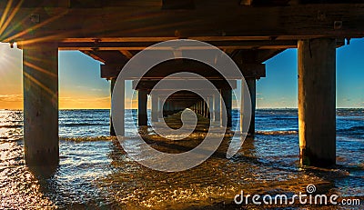 Under the pier at beautiful golden orange sunset Stock Photo