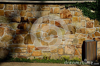 Under the shady treetops is a park beige, yellow sand path from a sandstone wall. perennials bloom there and there are several mod Stock Photo