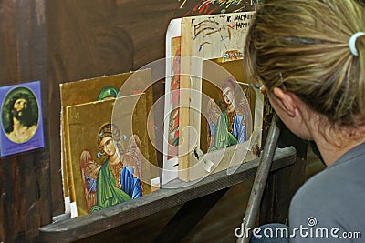 Under supervision of a monk a student is busy painting an icon Editorial Stock Photo