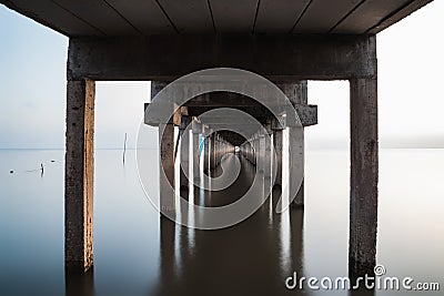 under view of bridge extended into the sea with water reflection Stock Photo