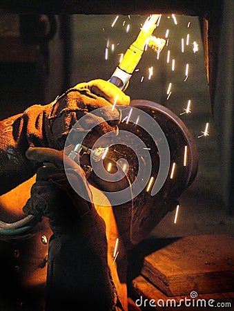 Underneath look at a welder at work on a huge mining dredge. Stock Photo