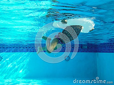 underwater photo of girl swimming in pool with circular floating Stock Photo