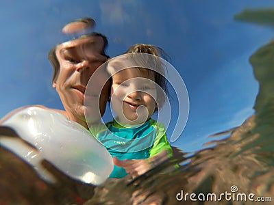 Underwater view of a father and her daughter with distorted face Stock Photo