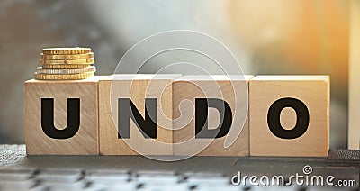 Undo word on wooden cubes with letters, and stack of coins. Technical issue computer program concept. Lifestyle and state of mind Stock Photo