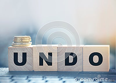 Undo word on wooden cubes with letters, and stack of coins. Technical issue computer program concept. Lifestyle and Stock Photo