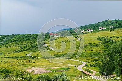 Undulating road thru green grass field hills Stock Photo