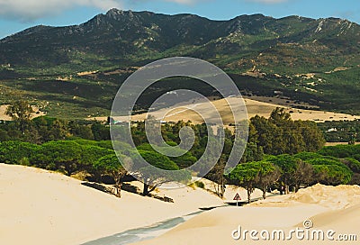 Undulating sand dunes against the backdrop of a majestic mountain in the horizon Stock Photo