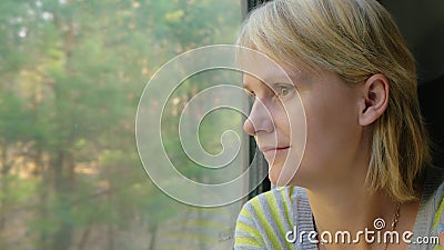 Une jeune femme voyage par chemin de fer, regarde la fenêtre les paysages banque de vidéos Une jeune femme voyage par chemin de fer, regarde la fenêtre les paysages banque de vidéos
