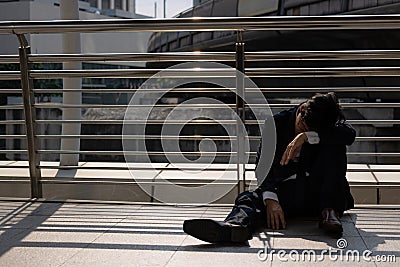 Unemployed stressed young Asian business man sitting on floor outdoors. Failure and layoff concept Stock Photo