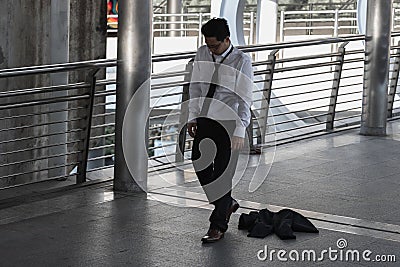 Unemployed stressed young Asian business man sitting on floor outdoors. Failure and layoff concept Stock Photo