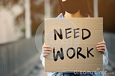 An unemployed women holding a paper sign writing a message saying she needs a job Stock Photo