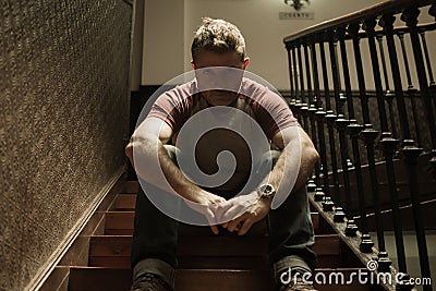 Unemployment and divorce - dramatic lifestyle portrait of sad and depressed man on his 40s sitting indoors on staircase thoughtful Stock Photo