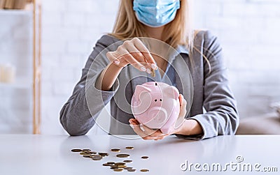 Unemployment during epidemic. Woman puts coins into piggy bank Stock Photo