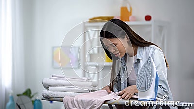 Unexperienced woman making hole on clothes during ironing process, housekeeping Stock Photo