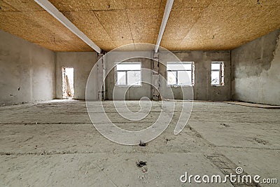 Unfinished apartment or house big loft room under reconstruction. Plywood ceiling, plastered walls, window openings, cement floor Stock Photo