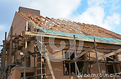 Unfinished brick house rooftop roofing construction attic trusses, wooden beams, eaves, timber, scaffolding. House roof wooden Stock Photo