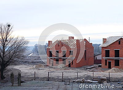 An unfinished brick houses with a wooden roof frame is still under construction. A building site Stock Photo