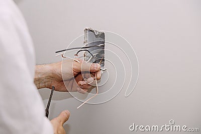 Unfinished electrical mains outlet socket with electrical wires and connector installed in plasterboard drywall Stock Photo