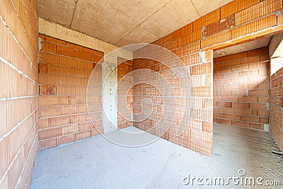 Unfinished room interior of building under construction. Brick red walls. New home Stock Photo