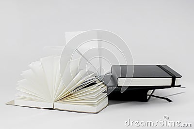 Unfold and closed small notebooks lie on top of each other. Fan open notepad with blank light beige pages. White back. Sketchbook Stock Photo